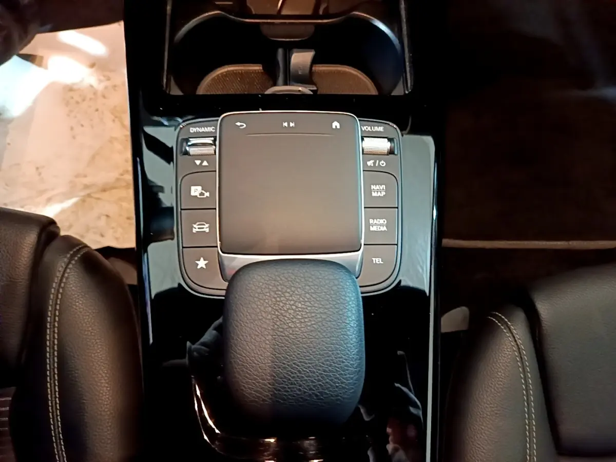 Vue plongeante sur la console centrale noire brillante avec pavé tactile et levier de vitesse cuir dans une Mercedes CLA 180 d gris clair.