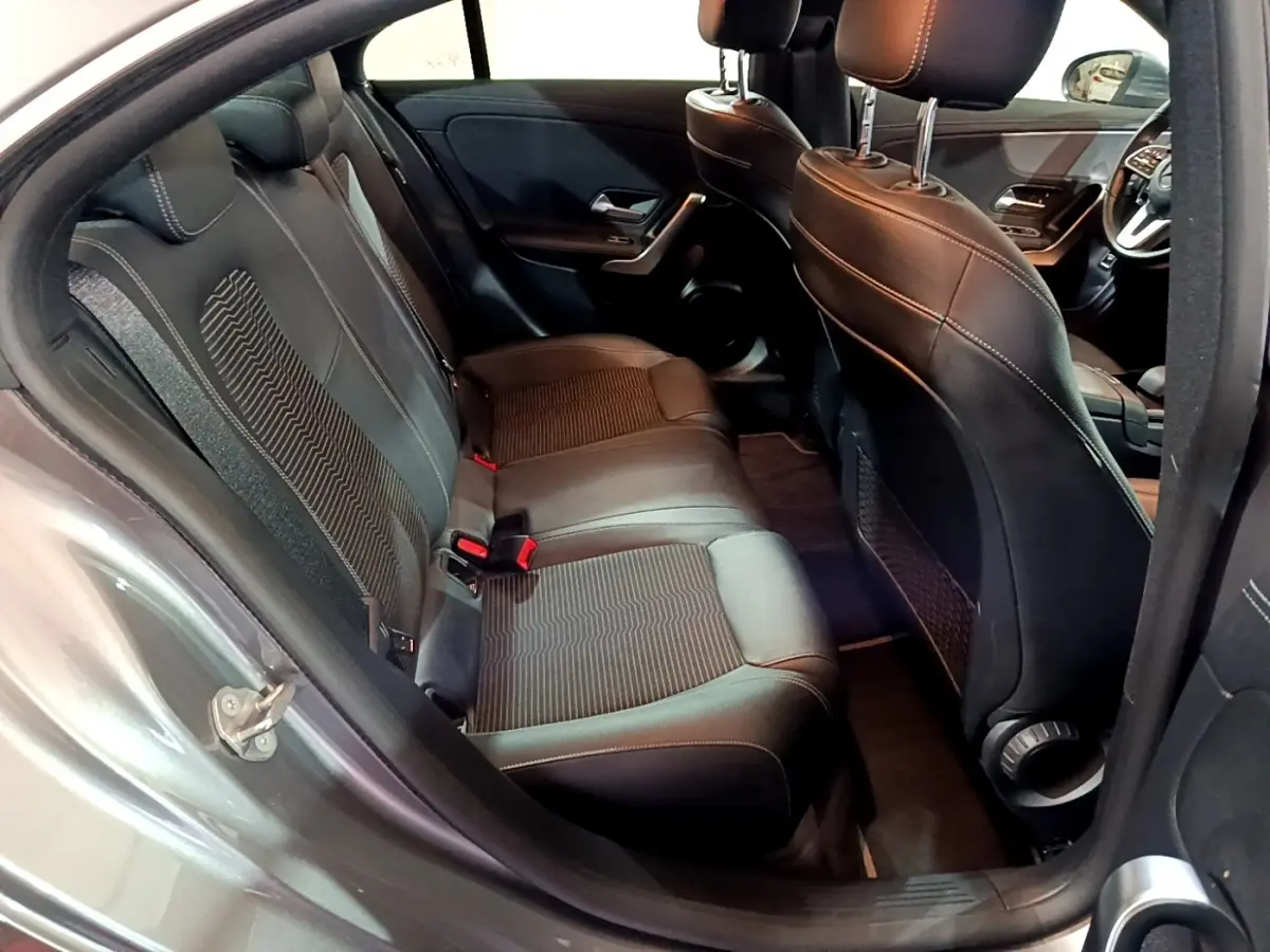 Vue intérieure côté arrière gauche sur les sièges noirs en cuir et tissu du Mercedes CLA 180 d Business Line gris clair.