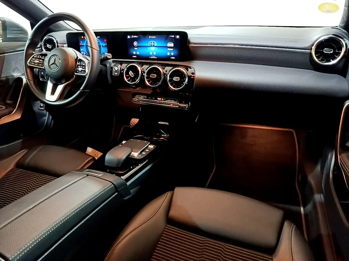 Vue intérieure avant droite de la Mercedes CLA 180 d Business Line 2021, tableau de bord noir avec écran tactile et volant cuir.