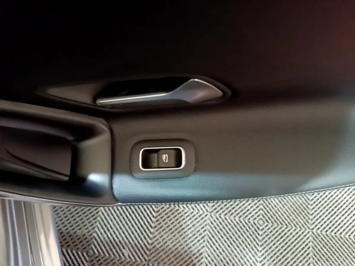 Détail de la commande d'ouverture du coffre sur la portière intérieure noire d'une Mercedes CLA 180 d Business Line.