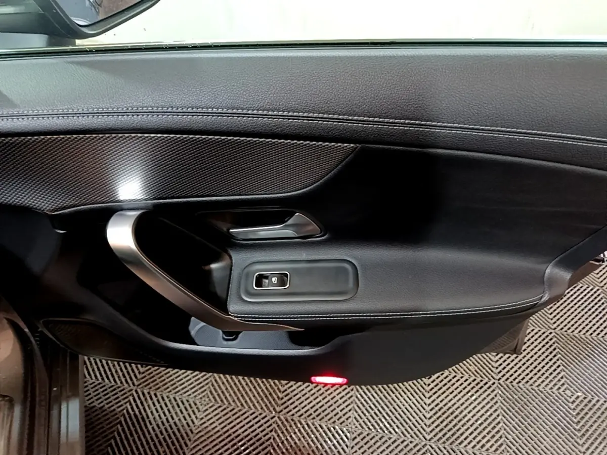 Gros plan sur la porte intérieure côté gauche d'une Mercedes CLA 180 d Business Line 2021 en gris clair, avec insert carbone et éclairage rouge.