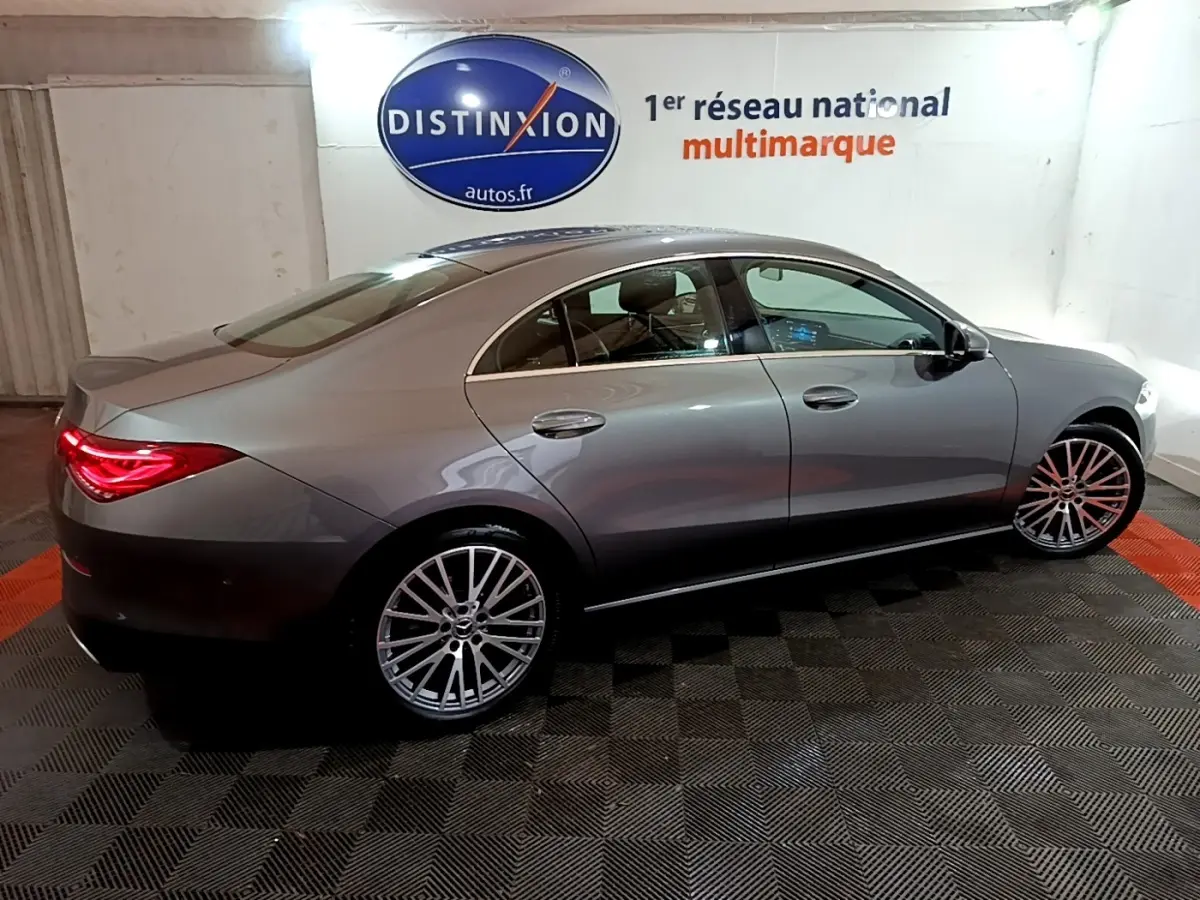 Vue latérale droite d'une Mercedes Classe CLA 180 d Business Line gris clair avec jantes alliage et feux arrière LED allumés.