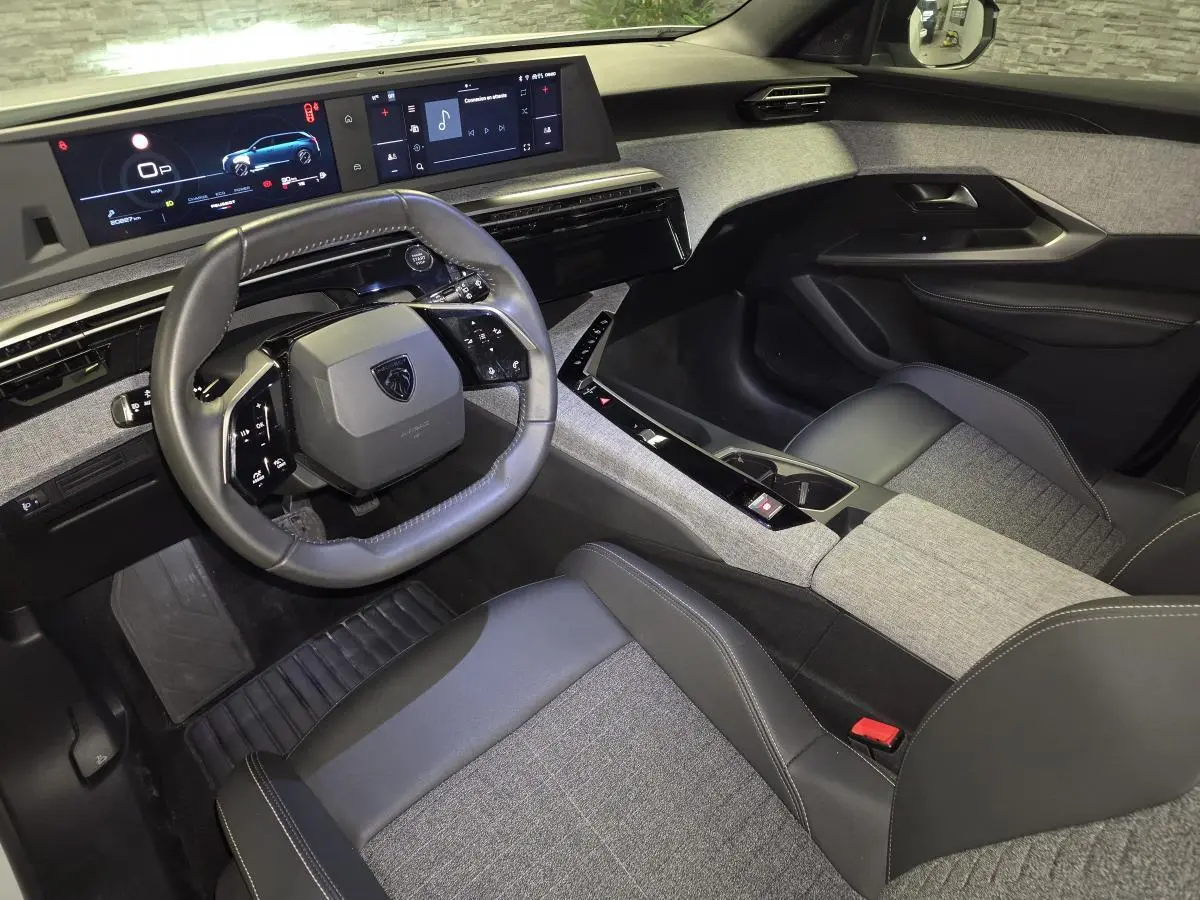 Vue intérieure côté conducteur du Peugeot 5008 2025, volant compact cuir noir et tableau de bord avec double écran HD.