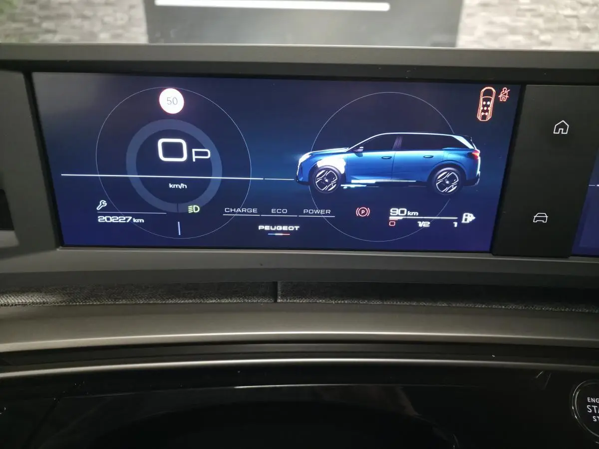 Affichage numérique du tableau de bord du Peugeot 5008 blanc, montrant la vitesse et la silhouette latérale du véhicule.