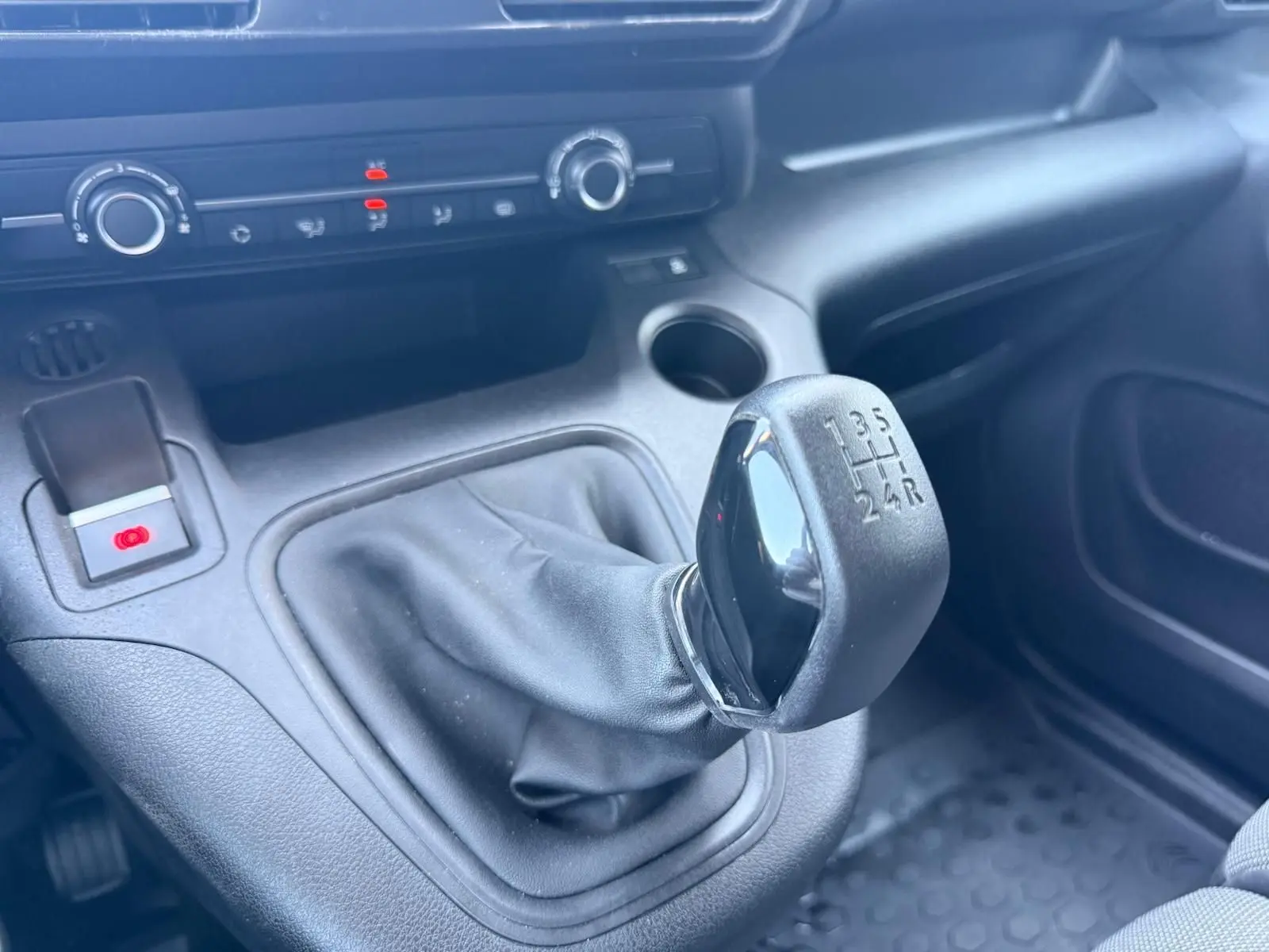 Gros plan sur le levier de vitesses manuel noir du Citroën Berlingo Van blanc, avec tableau de bord et commandes en arrière-plan.