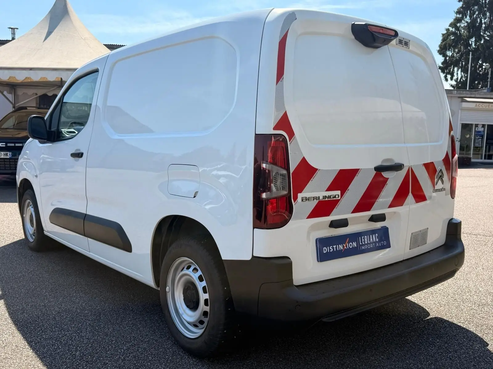Vue 3/4 arrière droite d’un Citroën Berlingo Van blanc avec bandes rouges réfléchissantes sur les portes arrière.