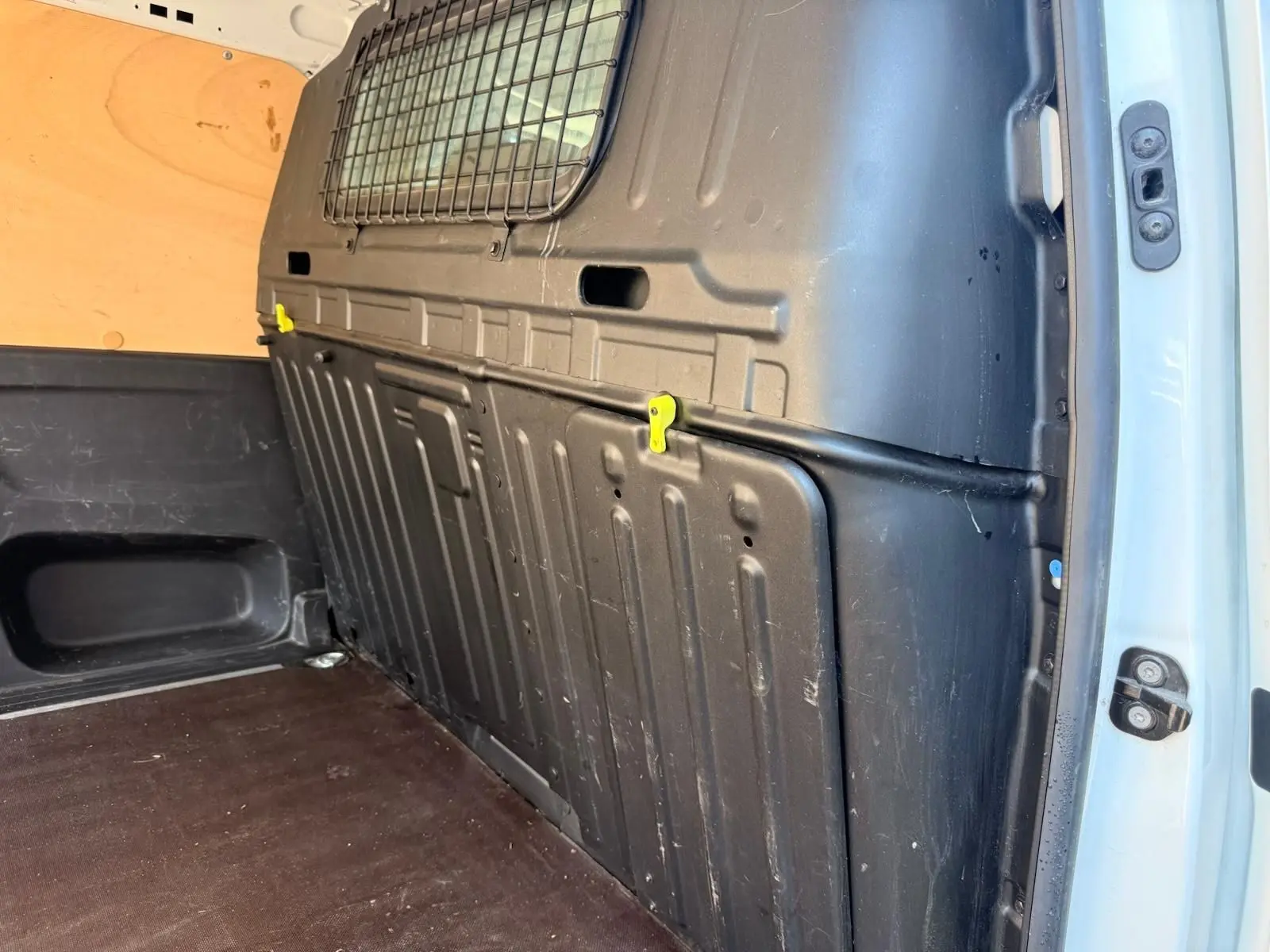 Vue intérieure arrière droite du Citroën Berlingo blanc 2020, montrant la cloison de séparation noire et le plancher en bois.