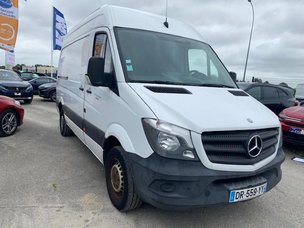 Vue 3/4 avant d'un Mercedes Sprinter blanc de 2015 avec pare-chocs noir et plaques françaises sur parking.