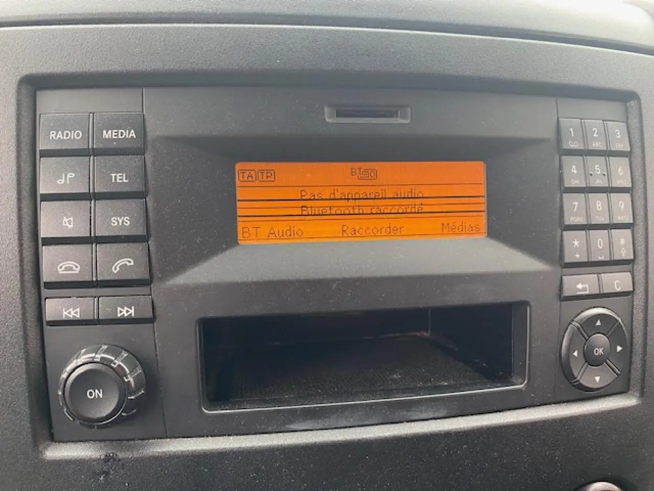 Affichage central orange du système audio du Mercedes Sprinter Fourgon blanc, vue rapprochée du tableau de bord.