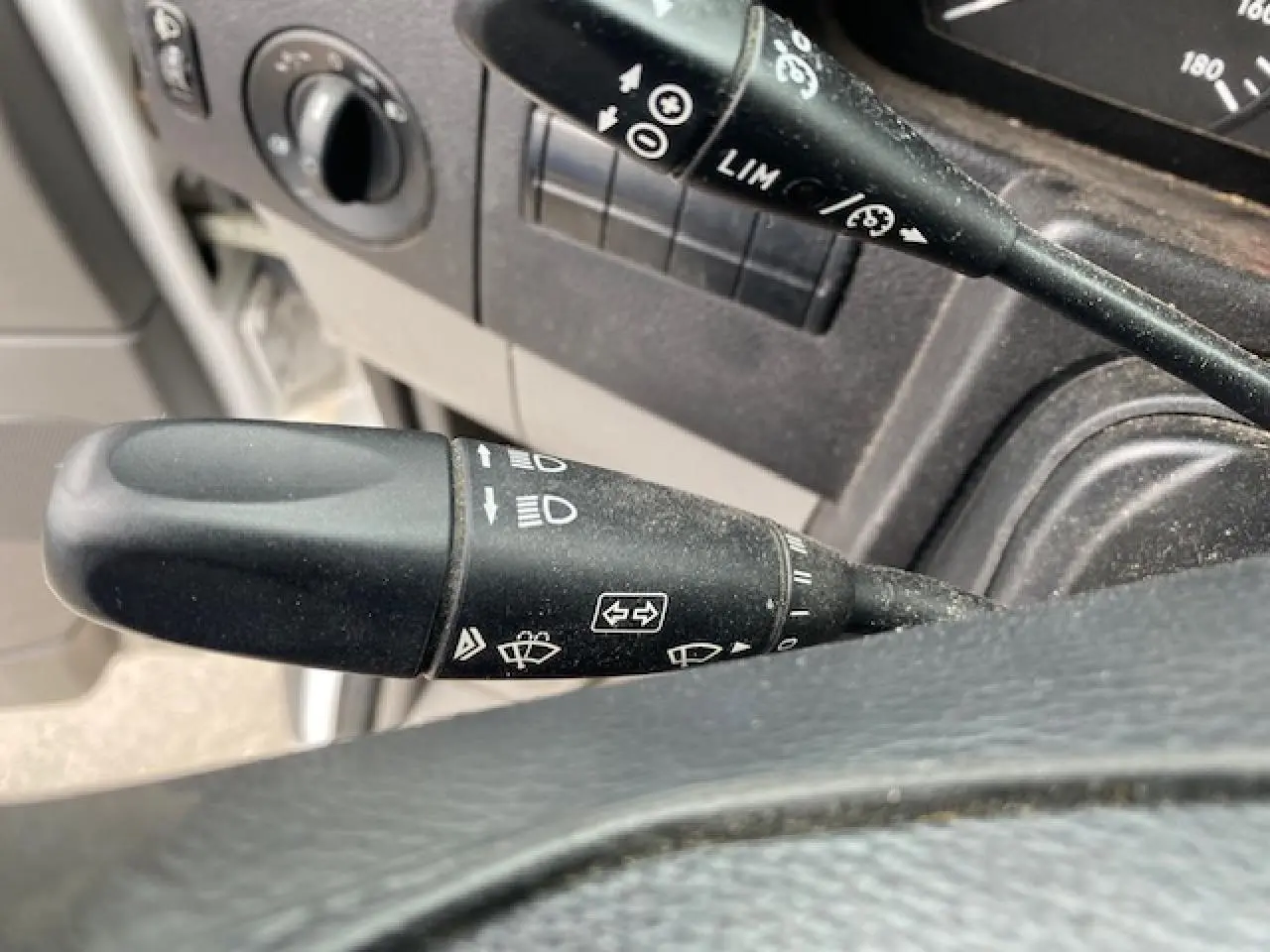 Gros plan sur la commande de clignotants et régulateur de vitesse du tableau de bord d'un Mercedes Sprinter blanc de 2015.