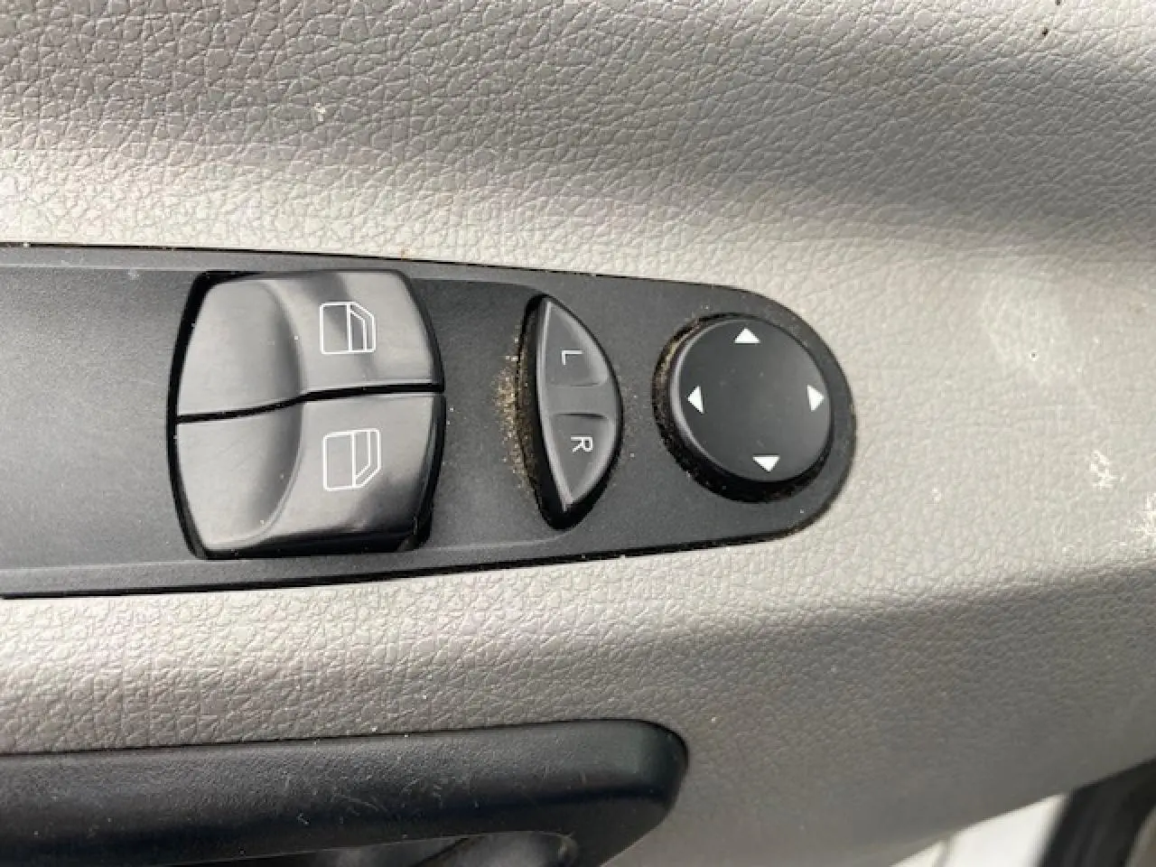 Boutons de commande des lève-vitres et réglages électriques des rétroviseurs sur la porte côté conducteur d’un Mercedes Sprinter blanc.