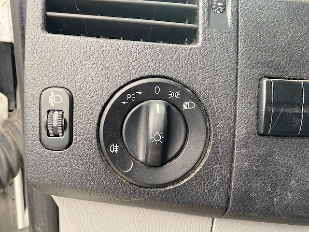 Gros plan sur le bouton de commande des phares du tableau de bord noir du Mercedes Sprinter Fourgon blanc de 2015.