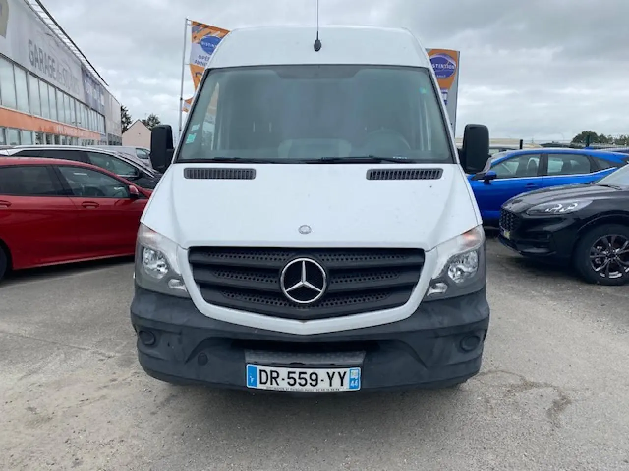 Vue frontale d'un Mercedes Sprinter blanc avec calandre noire et plaque d'immatriculation française visible.