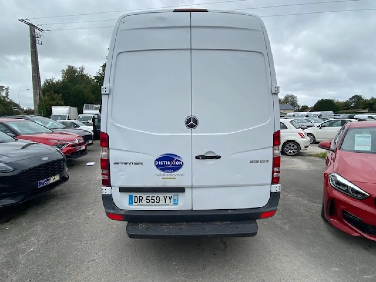 Vue arrière d'un Mercedes Sprinter fourgon blanc de 2015 avec plaques françaises et logo Distinxion visible.