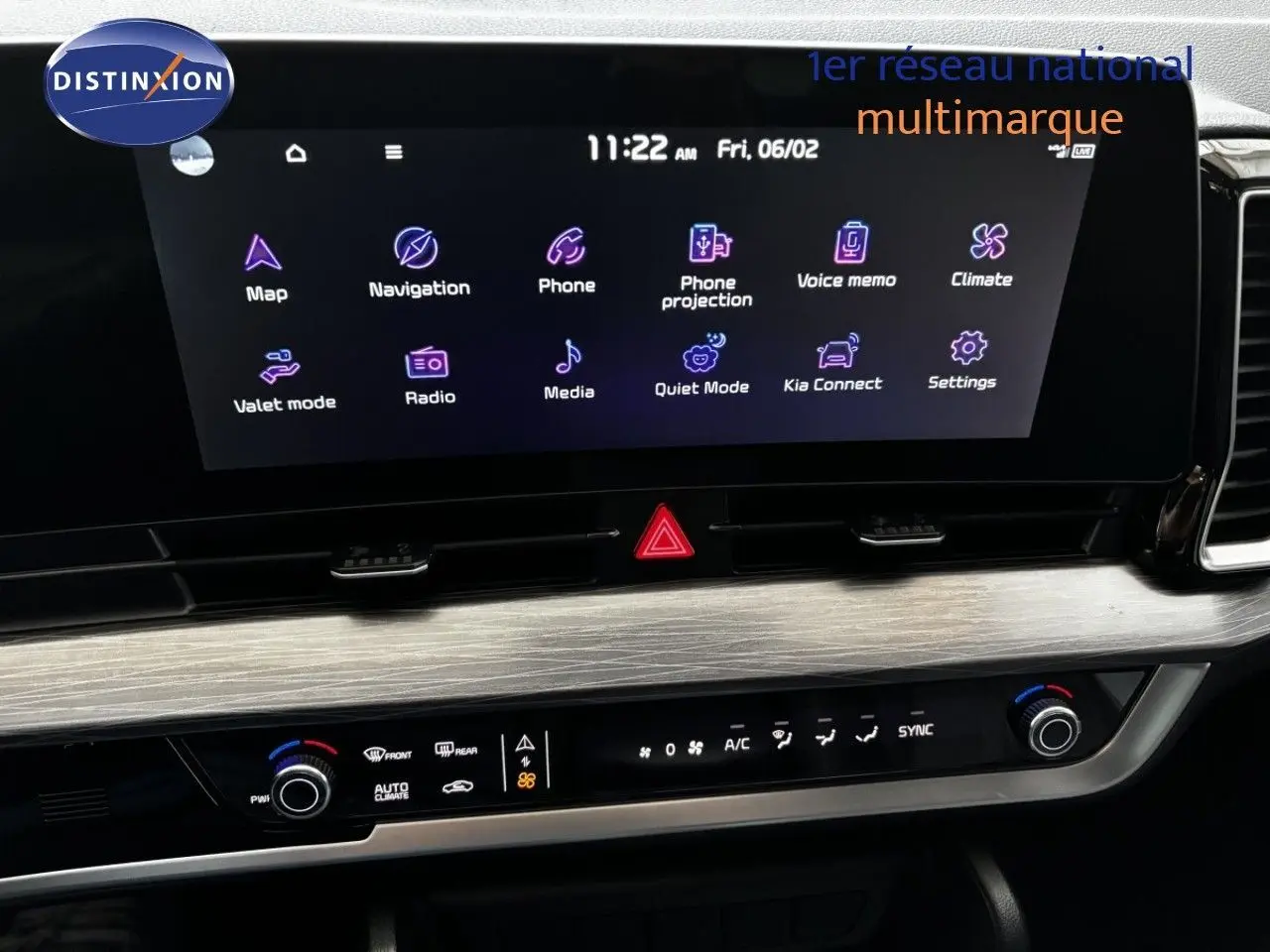 Vue rapprochée de l’écran tactile et de la console centrale du Kia Sportage blanc nacré, affichant les commandes multimédias et climatiques.