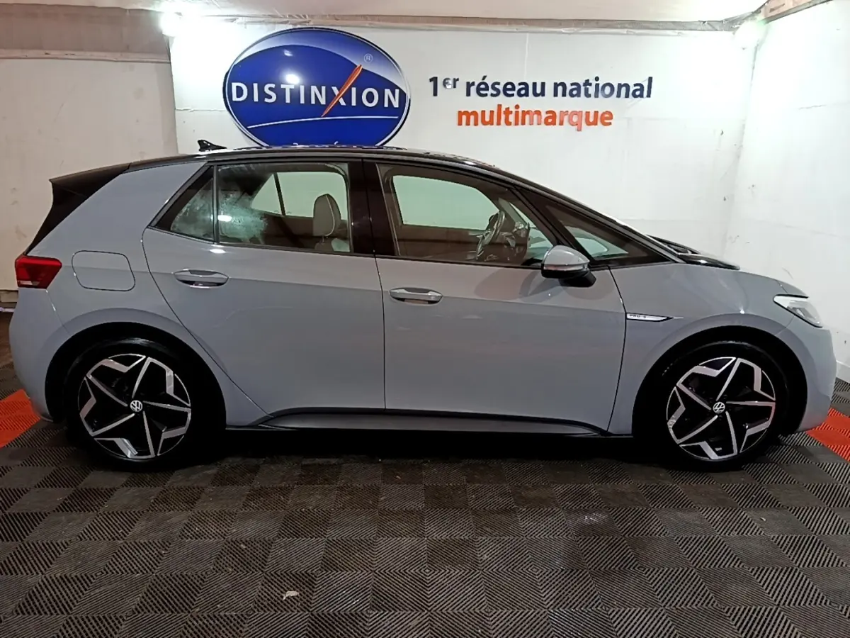 Vue de profil côté gauche d'une Volkswagen ID.3 gris foncé avec jantes noires et argentées dans un garage.