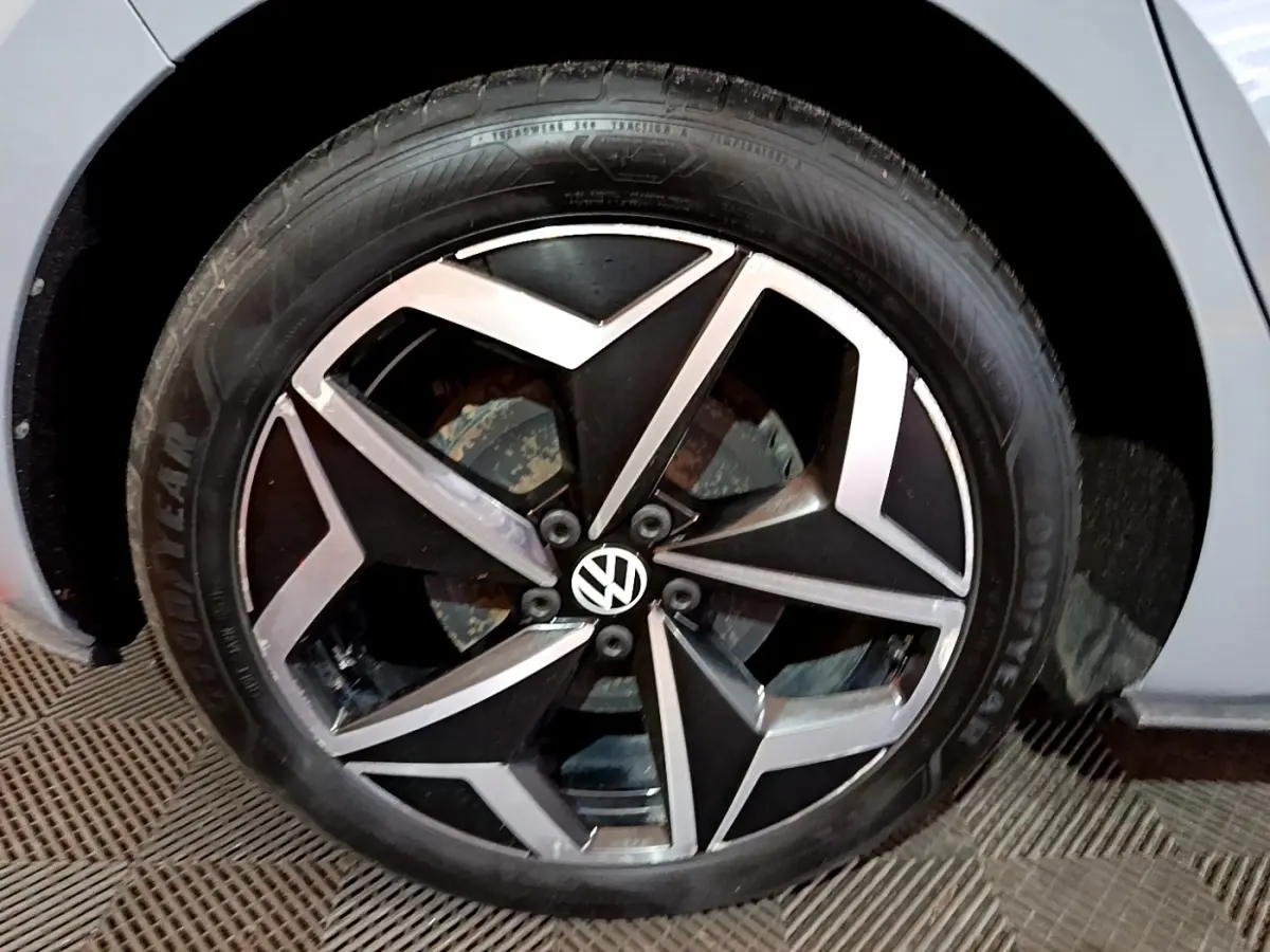 Gros plan sur la jante alliage noir et argent avec logo Volkswagen d'une Volkswagen ID.3 gris foncé.