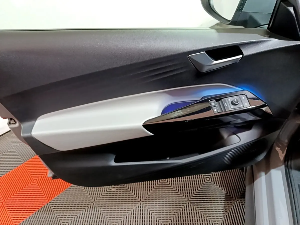 Vue rapprochée de la porte côté conducteur du Volkswagen ID.3 77 kWh Pro S gris foncé, avec commandes électriques et éclairage bleu.