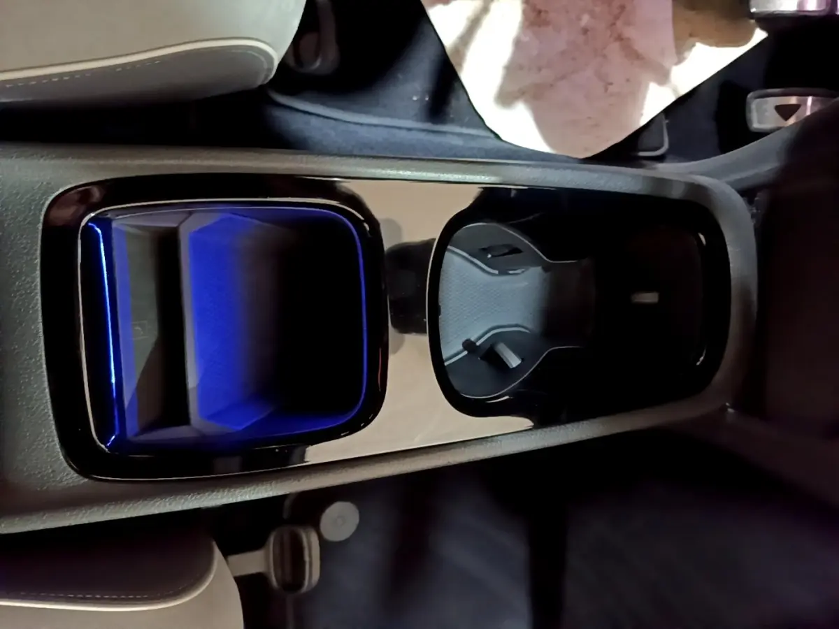 Vue rapprochée de la console centrale du Volkswagen ID.3 77 kWh Pro S, avec porte-gobelets et éclairage bleu intérieur.