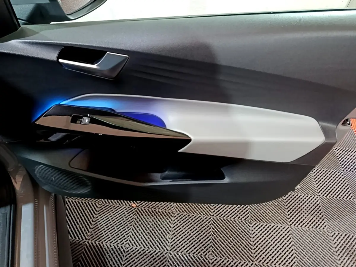 Vue intérieure du panneau de porte côté conducteur du Volkswagen ID.3 77 kWh Pro S avec éclairage d'ambiance bleu et garniture bicolore.