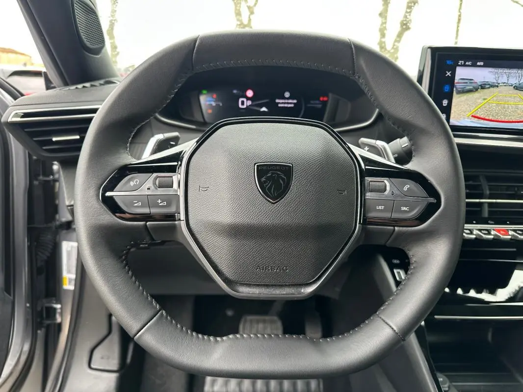 Vue rapprochée du volant cuir noir du Peugeot 2008 Hybrid 136 e-DCS6 Allure avec commandes intégrées et écran tactile visible.