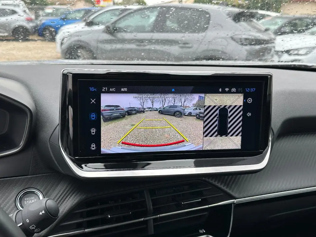 Vue intérieure centrée sur l'écran tactile affichant la caméra de recul du Peugeot 2008 gris avec tableau de bord noir.