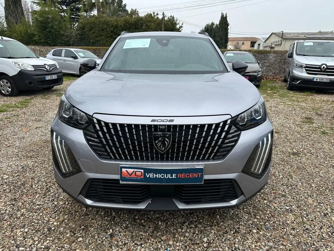 Vue avant d'un Peugeot 2008 gris 2025 avec calandre distinctive et feux LED verticaux allumés.