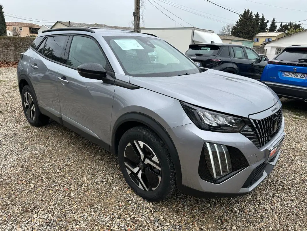 Peugeot 2008 Hybrid gris en 3/4 avant droit, avec barres de toit et jantes alliage 17 pouces visibles.