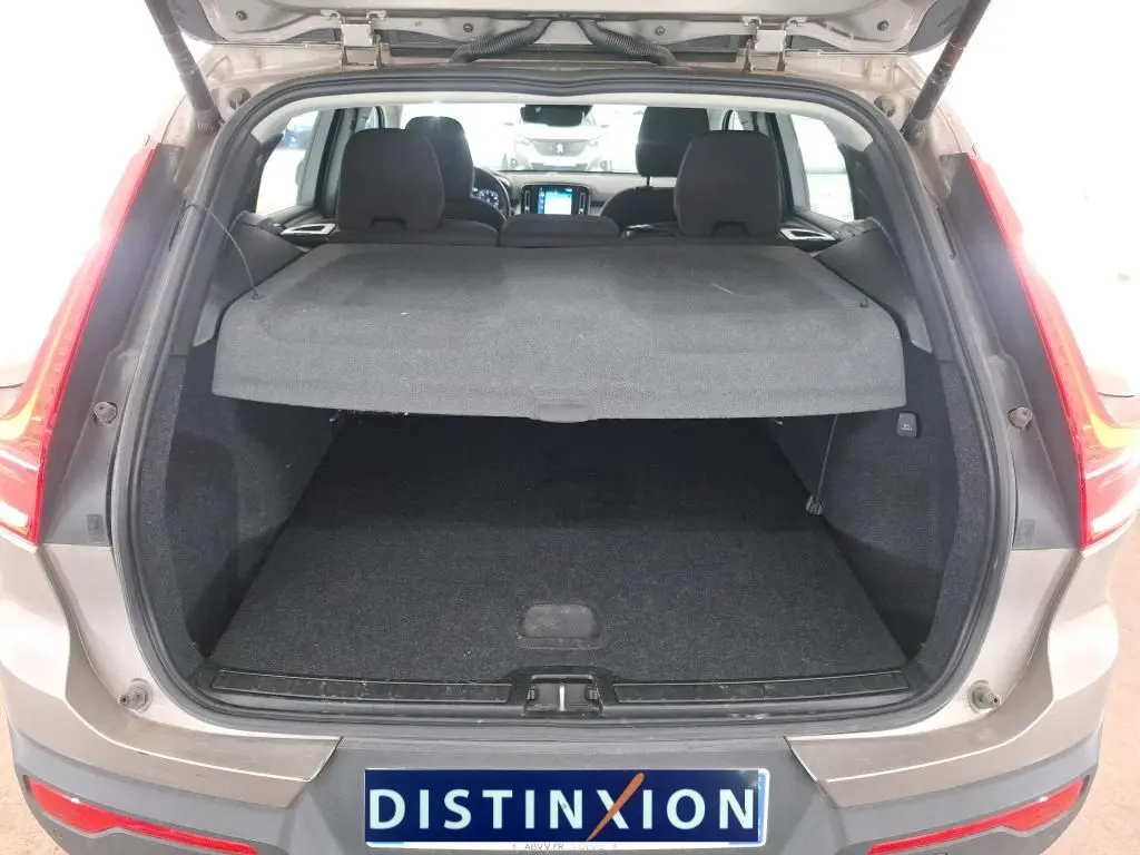 Coffre ouvert vu de l'arrière d'un Volvo XC40 marron clair 2021, avec cache-bagages en place et intérieur noir.
