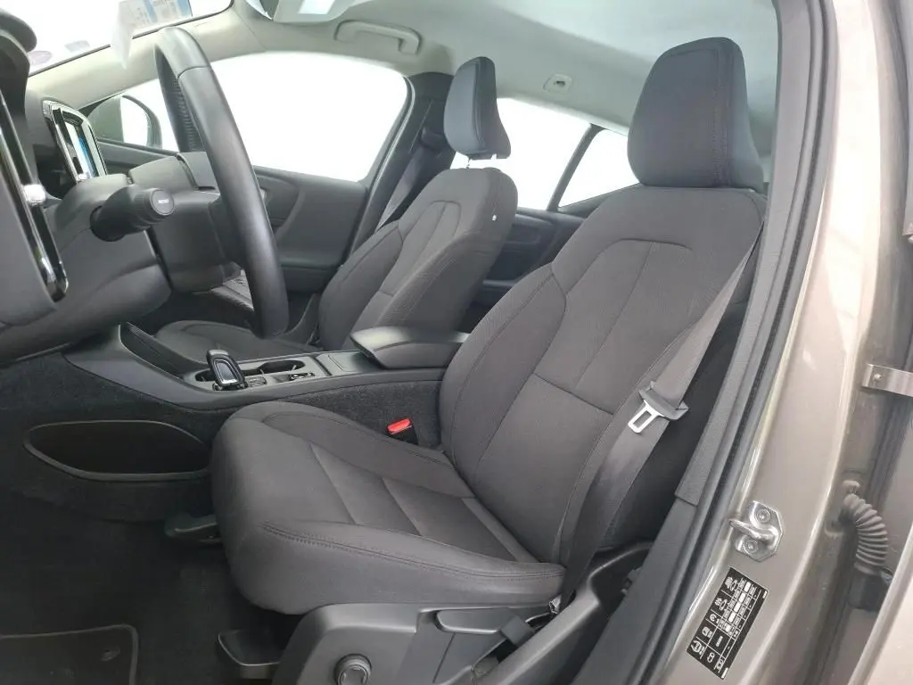 Vue intérieure côté conducteur du Volvo XC40 marron clair 2021, montrant les sièges avant en tissu gris et le tableau de bord.