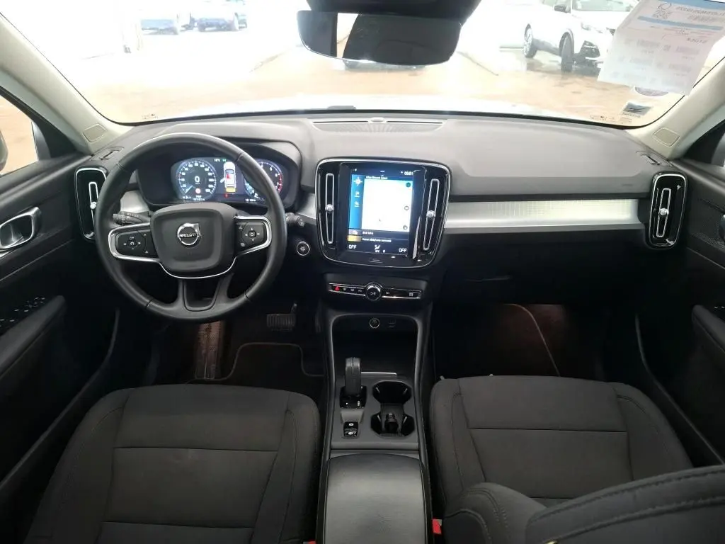 Vue intérieure avant du Volvo XC40 Momentum 2021, tableau de bord noir avec écran tactile central et volant multifonction.