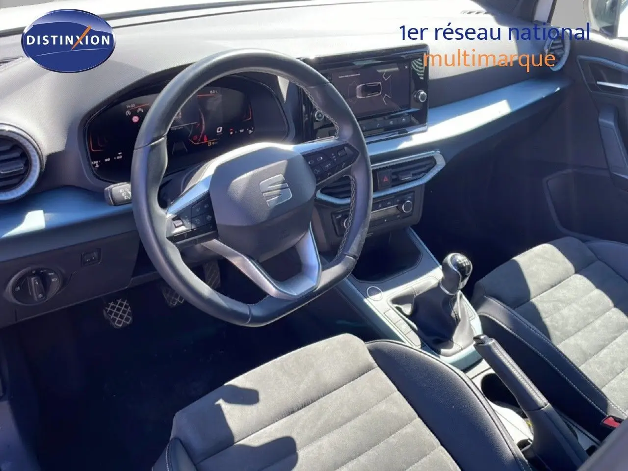 Vue intérieure côté conducteur du SEAT Arona 2025, volant cuir multifonction et levier de vitesses manuelle visibles.