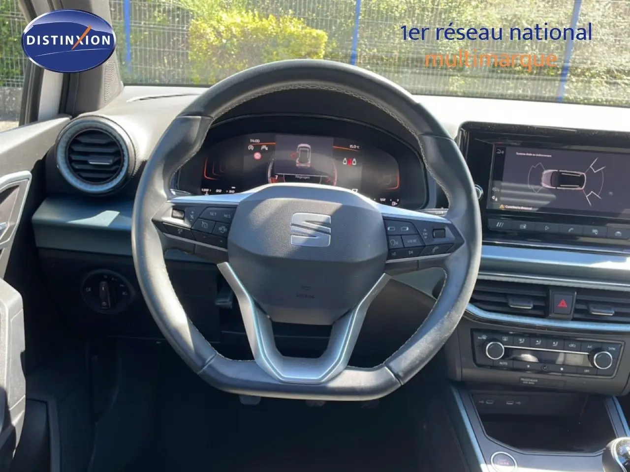 Vue intérieure centrée sur le volant cuir multifonction du SEAT Arona 2025 avec tableau de bord numérique et écran tactile.