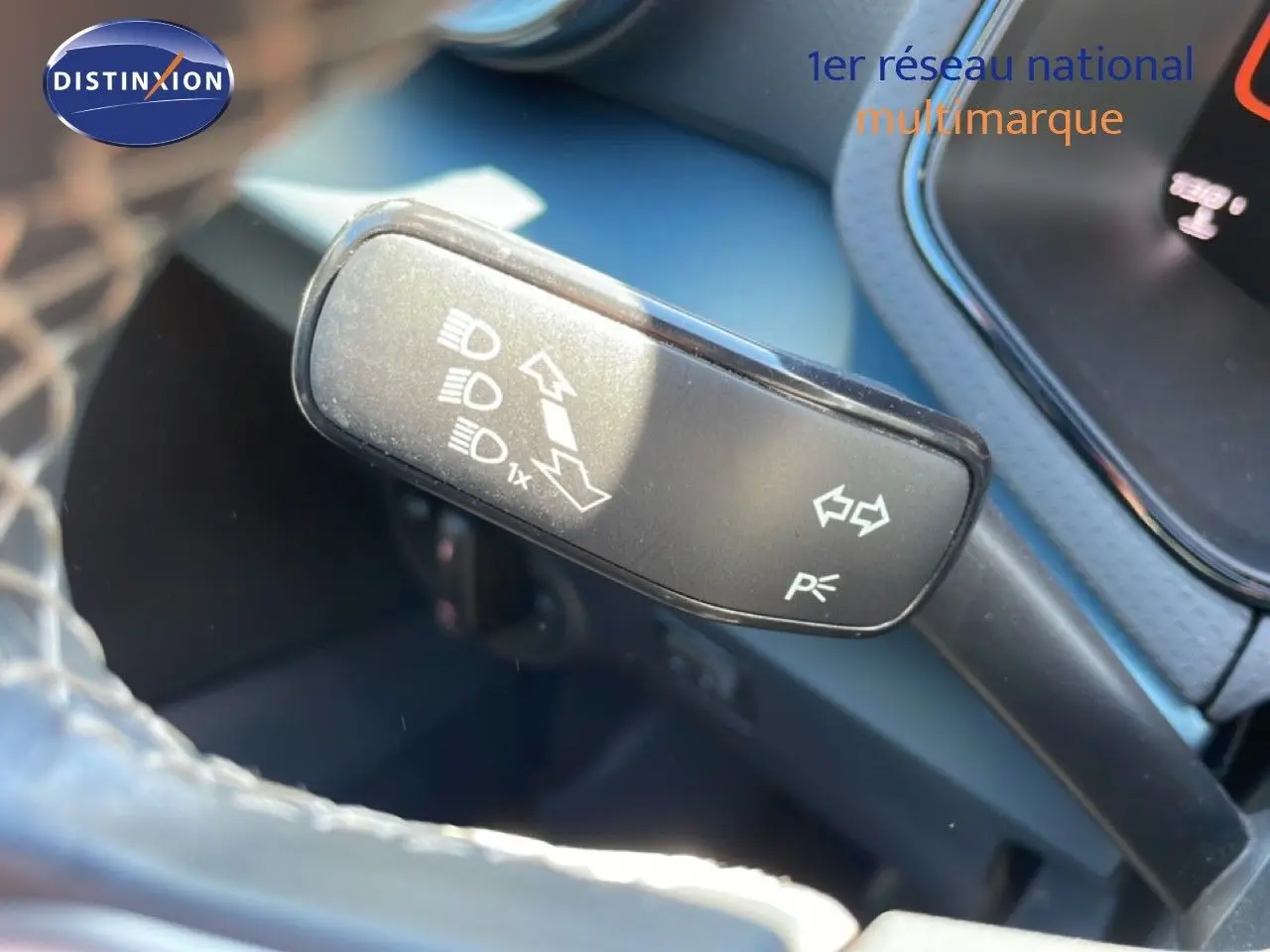 Gros plan sur la commande des clignotants et feux du SEAT Arona 2025, intérieur noir avec volant partiellement visible.