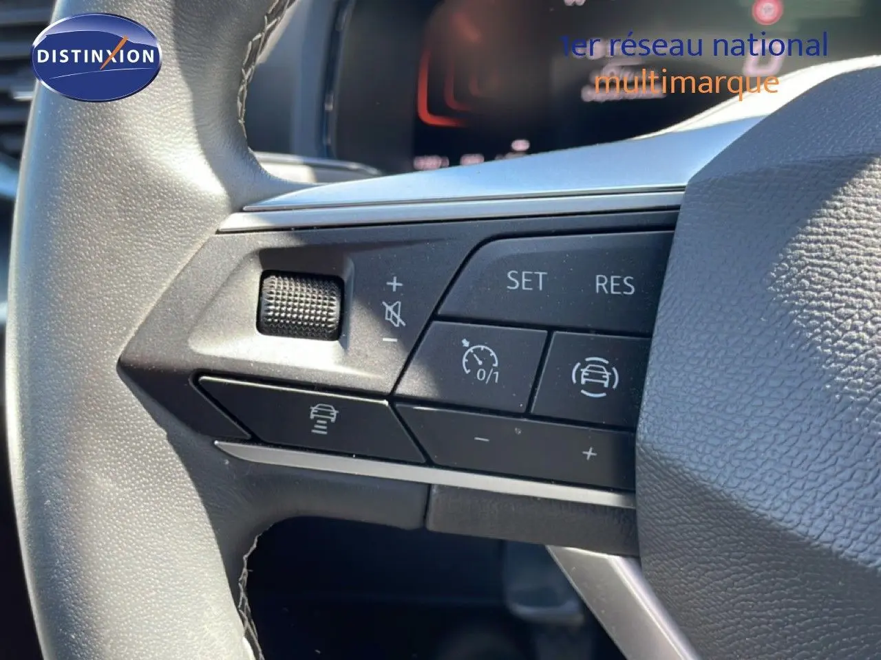 Gros plan sur les commandes au volant côté gauche du SEAT Arona 2025, volant cuir avec boutons de régulateur de vitesse.
