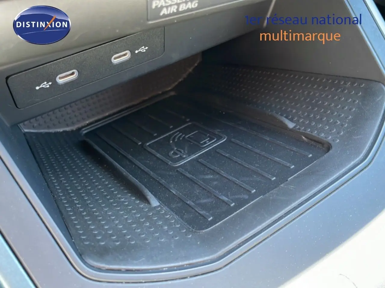 Gros plan sur le chargeur sans fil noir et les ports USB dans l’habitacle du SEAT Arona blanc toit noir, version 2025.