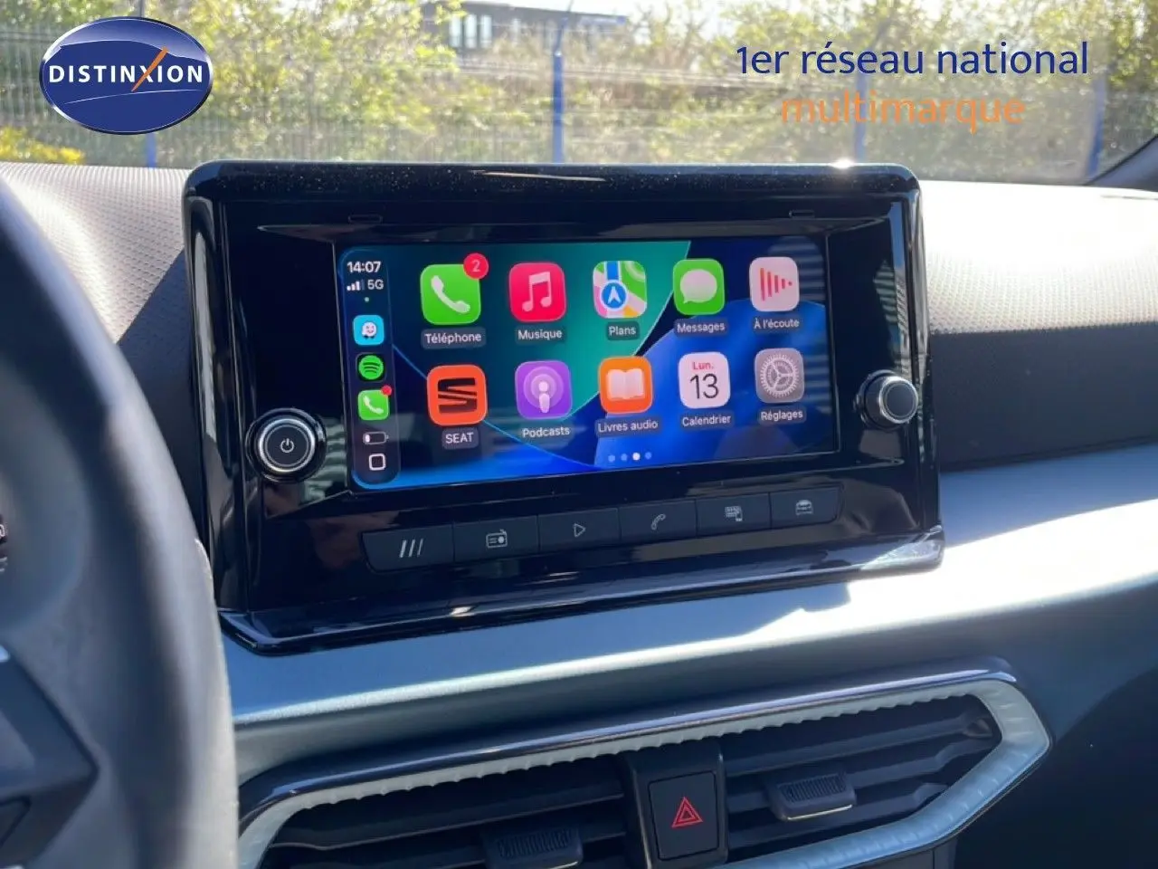 Vue rapprochée de l’écran tactile central du tableau de bord du SEAT Arona blanc avec toit noir, affichant les applications connectées.