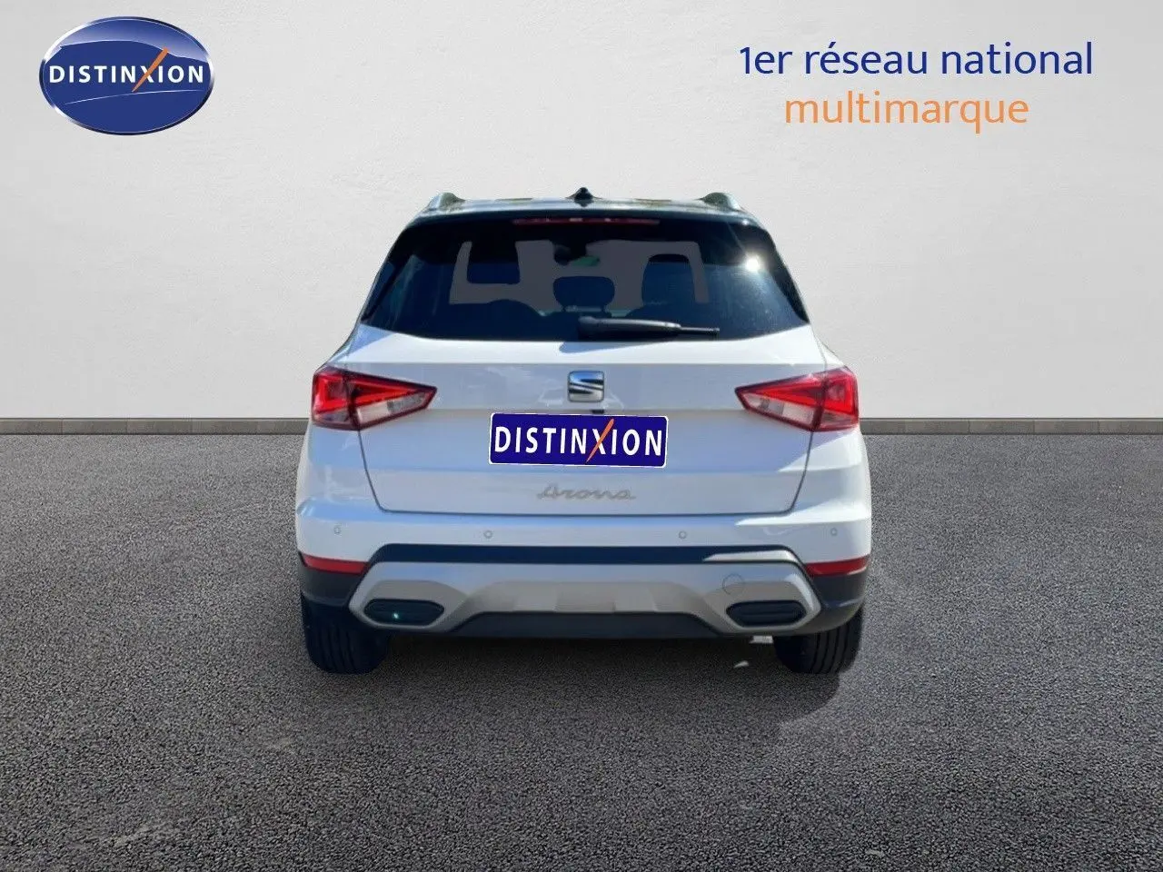 Vue arrière d'un SEAT Arona blanc avec toit noir, montrant les feux arrière et le pare-chocs arrière.