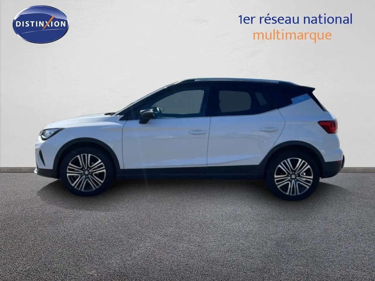Vue de profil droit d'un SEAT Arona blanc avec toit noir, roues alliage et lignes modernes sur fond neutre.