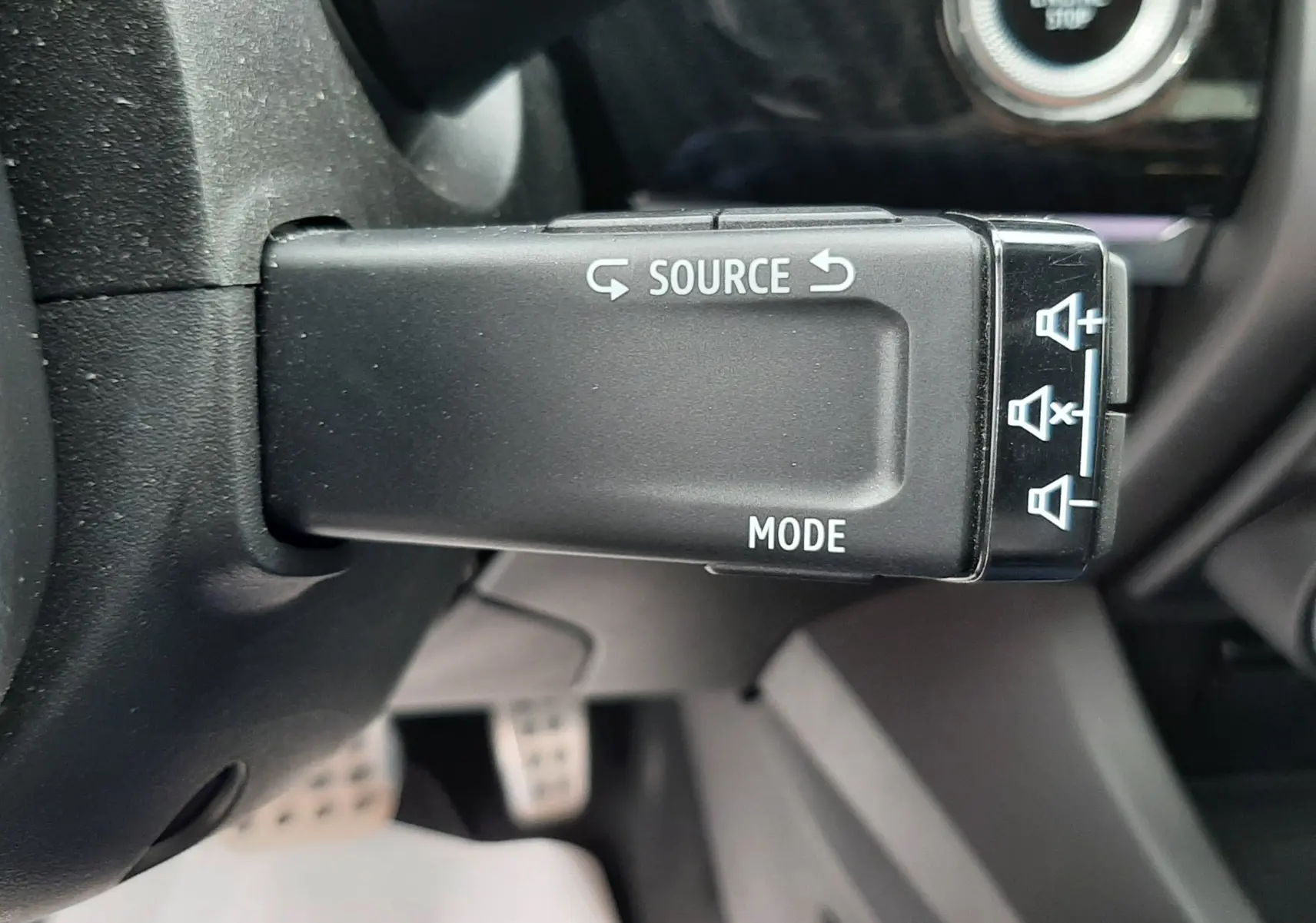 Gros plan sur la commande au volant gauche du Renault Arkana E-Tech 145ch RS-Line, avec bouton Start/Stop visible en arrière-plan.