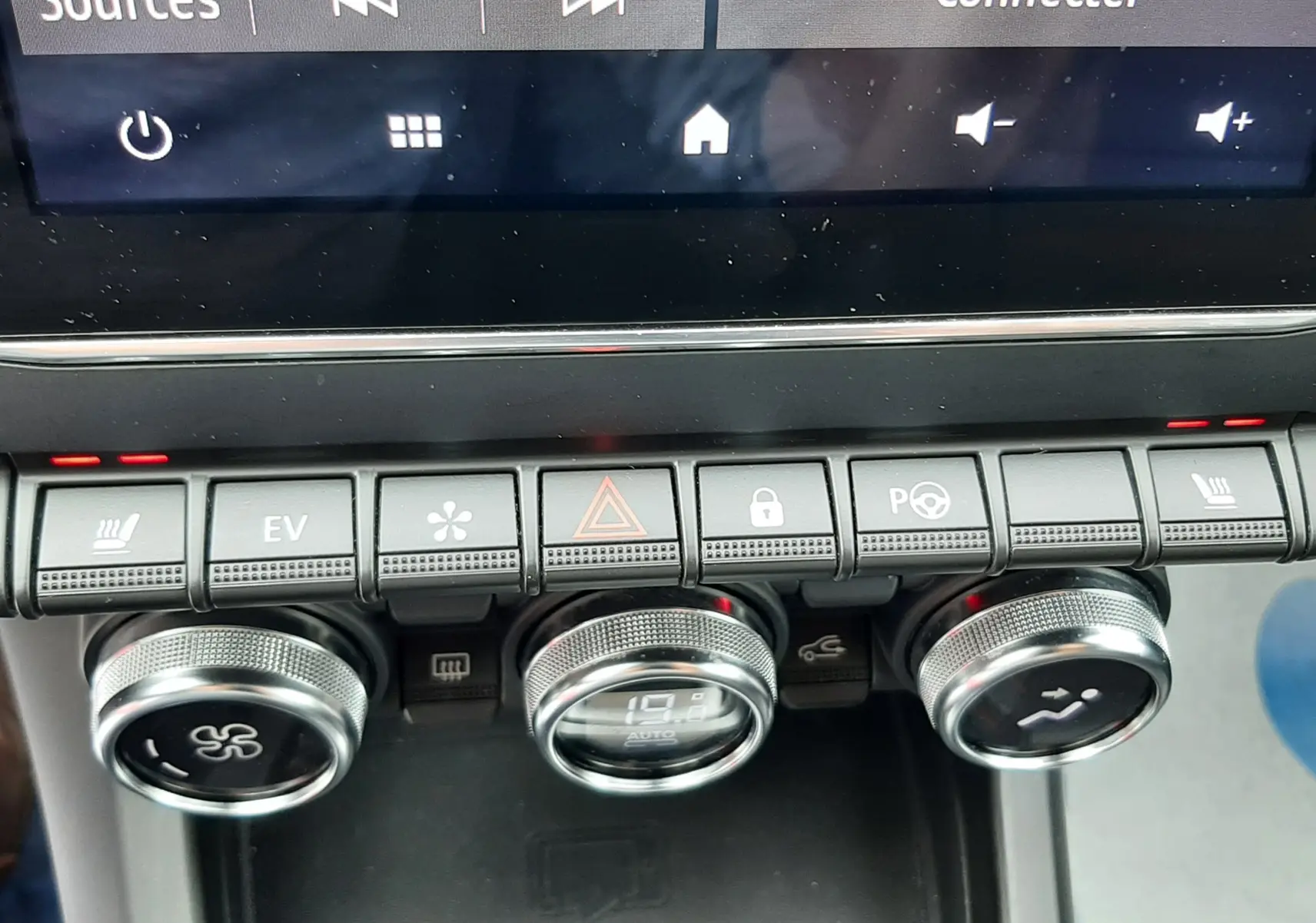 Vue rapprochée de la console centrale du Renault Arkana E-Tech bleu Zanzibar, montrant les commandes de climatisation et l’écran tactile.