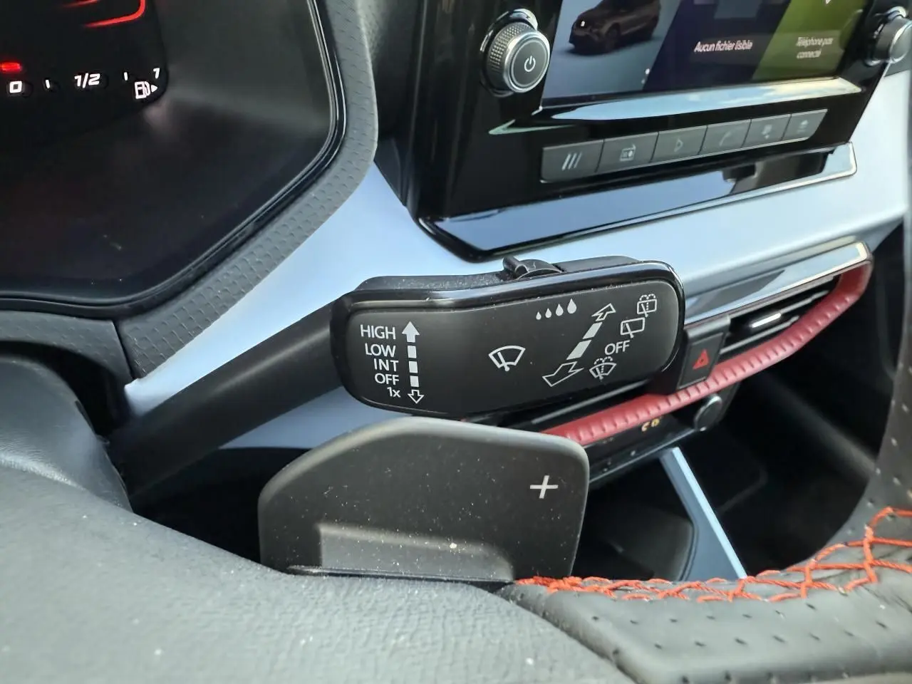 Gros plan sur la manette d’essuie-glace et palette de changement de vitesse côté gauche du tableau de bord noir avec surpiqûres rouges du SEAT Arona rouge.
