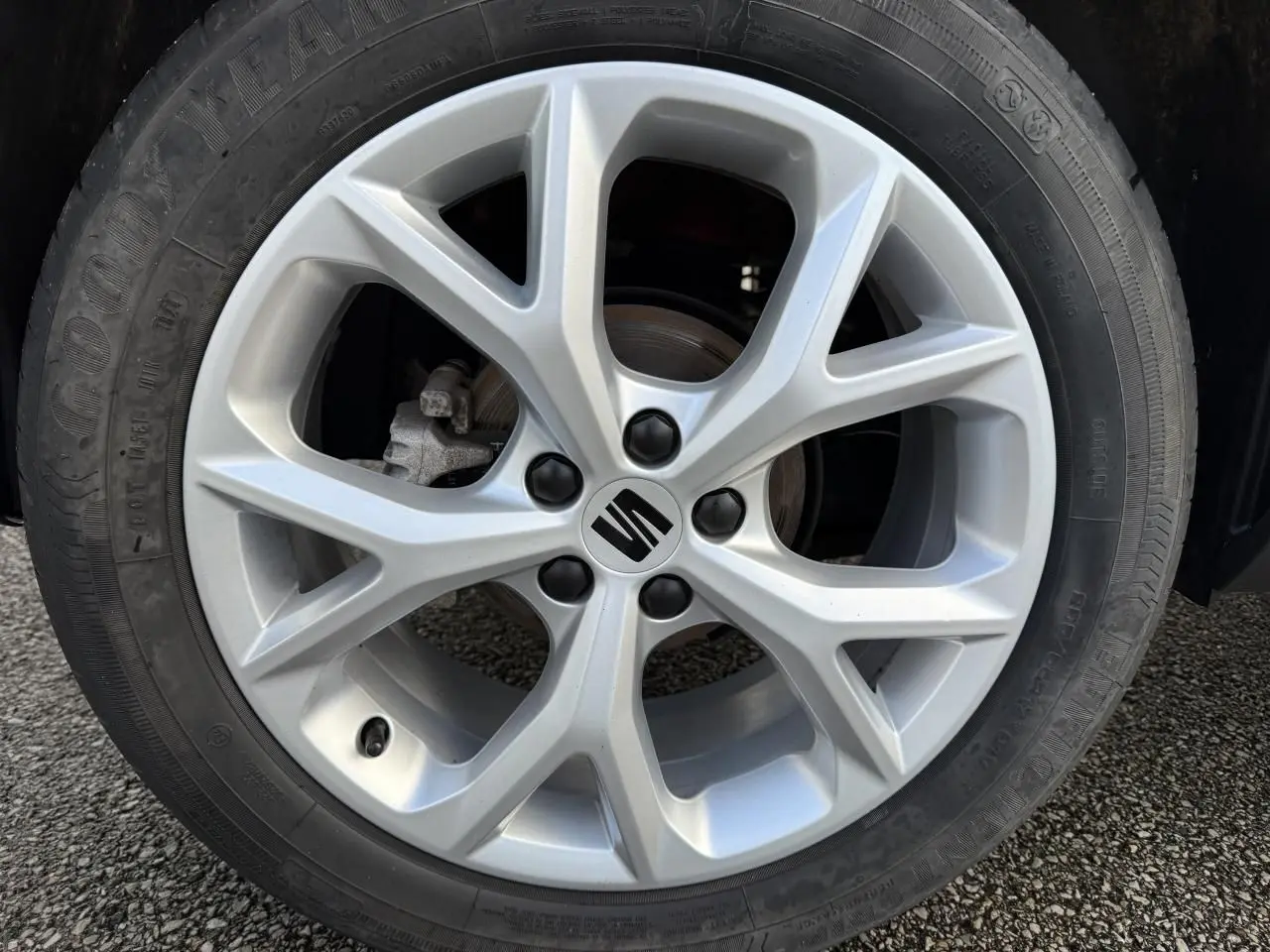 Gros plan sur la jante alliage argentée avec logo SEAT, pneu Goodyear monté sur un SEAT Arona rouge.