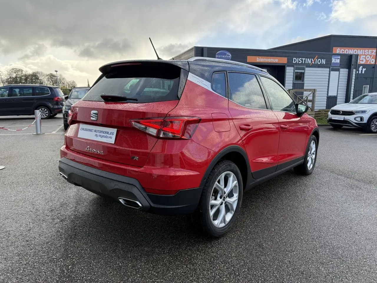 Vue 3/4 arrière droite d’un SEAT Arona rouge 2024 avec toit noir, jantes alliage et feux arrière LED triangulaires.