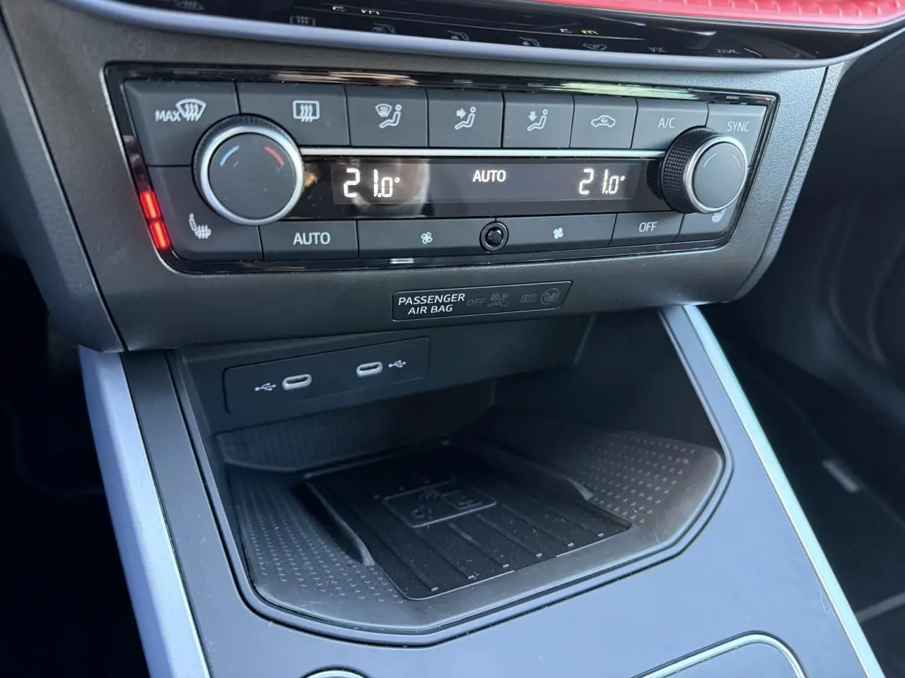 Gros plan sur la console centrale du SEAT Arona 2024, montrant la commande de climatisation et la station de recharge sans fil.