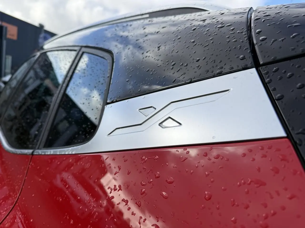 Détail du montant arrière droit rouge et noir du SEAT Arona 2024 avec insert décoratif argenté sous la pluie.