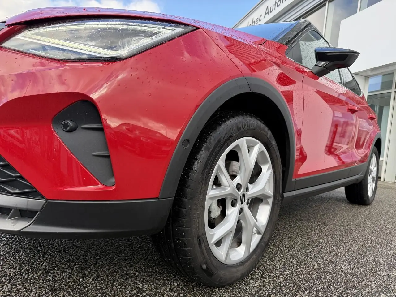 Vue en gros plan 3/4 avant droit d'un SEAT Arona rouge avec projecteur LED et jante alliage argentée.