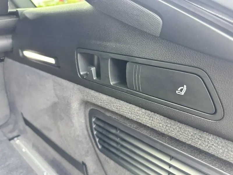 Détail du panneau intérieur côté gauche du coffre noir avec commande de siège rabattable sur Audi A6 Avant 2019.