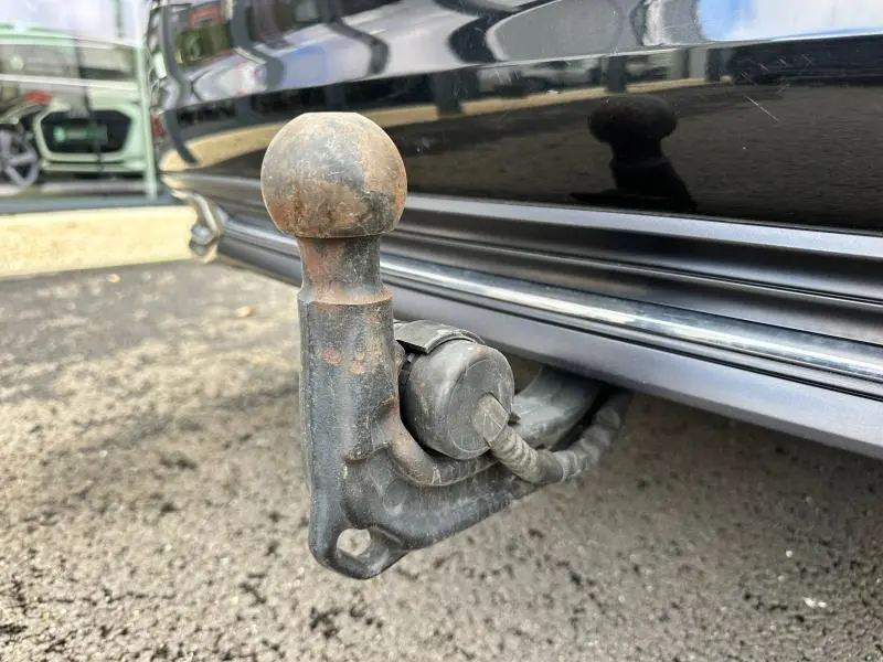 Gros plan sur l'attelage d'une Audi A6 Avant noir métal, vue côté gauche sous le pare-chocs arrière.