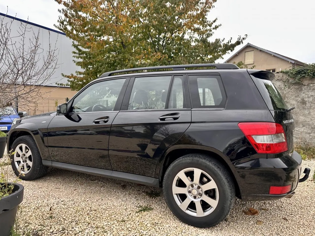 Mercedes GLK 220 CDI noir vu de profil côté gauche, avec barres de toit et jantes alliage visibles